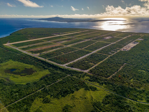 Aerial view of North Field Base with historic runways surrounded by dense tropical vegetation and the Pacific Ocean in Northern Tinian, Tinian, Northern Mariana Islands.