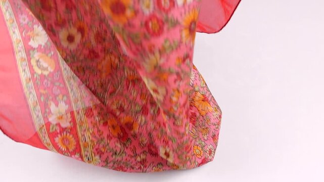 Traditional Indian silk fabric falls onto a white background. Floral pattern features pink and golden shades. Woven kashmiri scarf is perfect for fashion advertising.