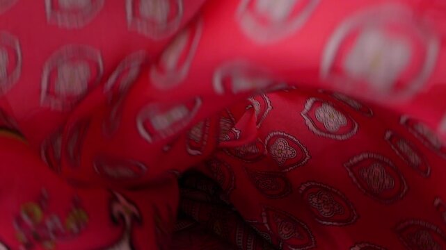 Silk scarf falls onto a white background. Bright red textile features oriental paisley patterns. Elegant fabric is perfect for fashion commercials and luxury brand advertising.