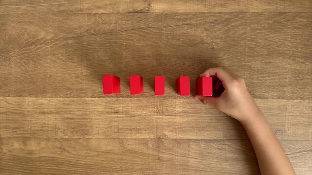 Child Hand Lines Up Red Wooden Blocks and Knocks Them Down Like Dominoes, 4K