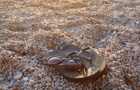Flip flop sandals and sun glass on the beach with pebbles by the blue sea summer beach accessories