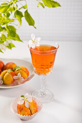 Fototapeta premium Refreshing glass of apricot tea or cocktail with a delicate flower and sugar-coated peach