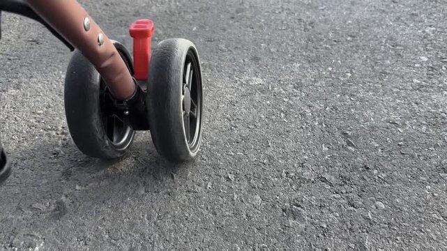 Close Up Stroller Wheels On Rough Asphalt Road