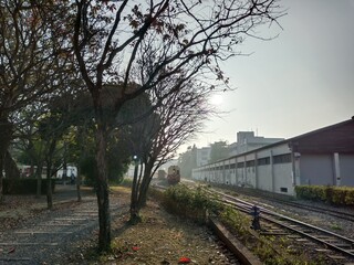 Fototapeta premium Vintage train on railway tracks at sunset with trees and buildings