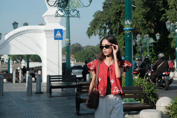 Fototapeta premium Fashionable Asian Woman Wearing Sunglasses in Historic Urban District