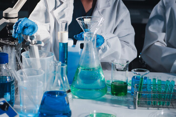 Fototapeta premium Female and Male Scientists Working on their Computers In Big Modern Laboratory. Various Shelves with Beakers, Chemicals and Different Technical Equipment is Visible.