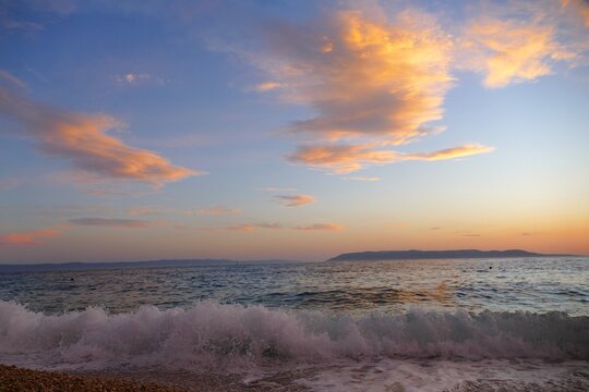 Waves on the wind with foam on the sea horizon with colorful clouds in sunset summer sunset background