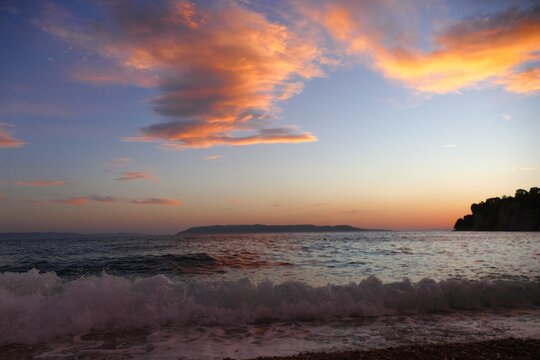 Waves on the wind with foam on the sea horizon with colorful clouds in sunset summer sunset background