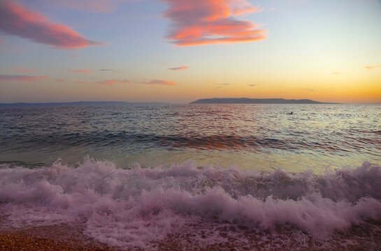 Waves on the wind with foam on the sea horizon with colorful clouds in sunset summer sunset background