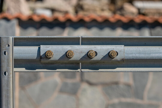 Close up of metal guardrail with bolts and industrial structure detail.