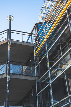 Modern apartment facade with construction scaffolding under clear sky representing urban development and renovation.
