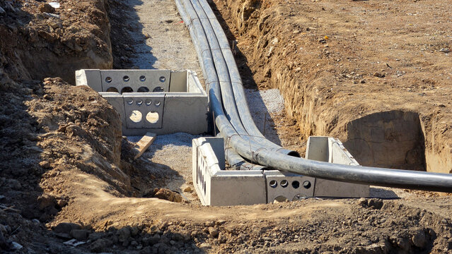Flexible high voltage power cable conduits routed through precast concrete utility chambers in open trench