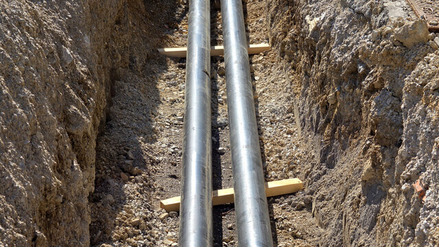 Parallel preinsulated heating utility pipelines laid inside deep earthen construction trench