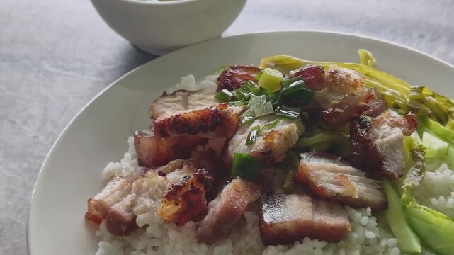 Close-up of a delicious plate of Vietnamese crispy pork belly with white rice and pickled mustard greens