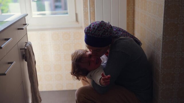 Mother kissing distressed toddler while providing comfort and reassurance, tender parenting moment highlighting attachment, emotional security, affection