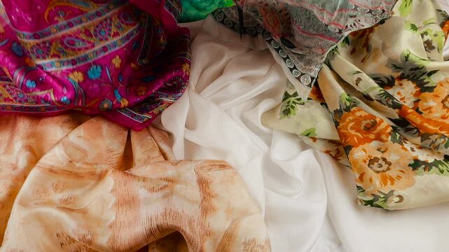 Colorful printed silk fabric falling onto textile background in slow motion. Oriental floral and paisley pattern details close up. Luxury texture ideal for fashion and apparel industry.