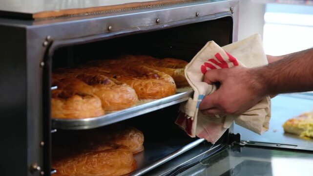 Close-up footage of freshly baked b&ouml;rek trays inside a bakery oven, showing golden pastry layers, traditional Turkish food preparation and restaurant-style baking process.