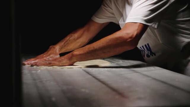 Close-up footage of hands sprinkling a crumbly nut filling over thin dough, capturing handmade pastry preparation, traditional dessert making and detailed bakery work on a covered surface.
