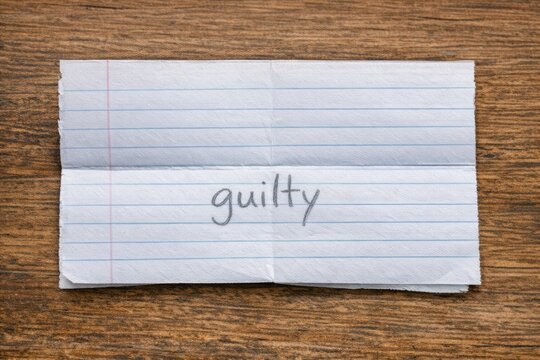 A piece of paper with the words 'guilty' written, perfect for representing a sense of responsibility or accountability