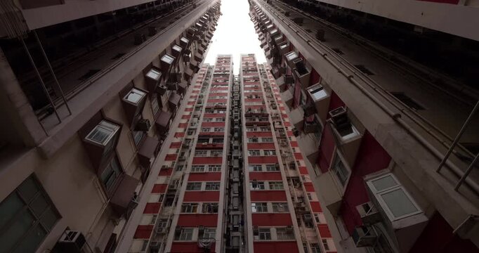 Dense old Hong Kong residential complex towering vertically, revealing packed urban living with clothes hanging from windows, showcasing geometric architectural patterns