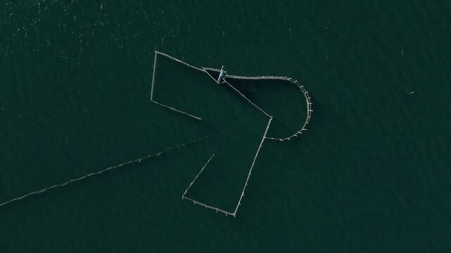 Aerial top down view of traditional fish trap structure in clear tropical waters. Ideal for environmental and cultural concepts.