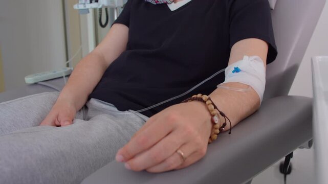 Patient receiving intravenous treatment in medical clinic with focus on infusion line, healthcare recovery concept highlighting care, treatment, resilience and wellness
