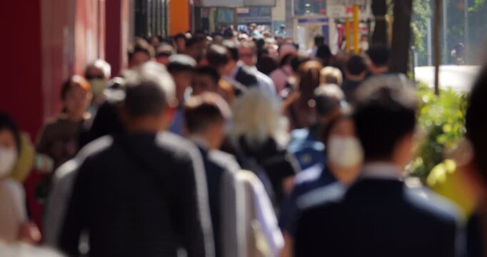 Slow motion blurred view of people and office workers walking at busy Nathan Road during lunchtime on sunny day. Defocused shot ensures no recognizable faces, clip suitable for commercial usage