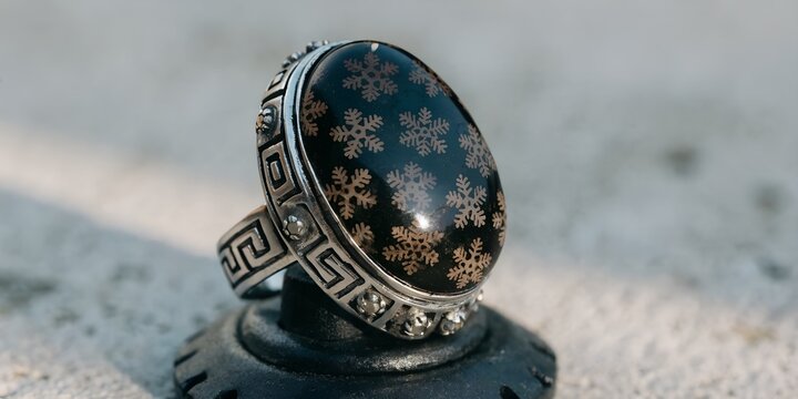 Traditional Indonesian Silver Ring with Black Fossilized Coral Agate Gemstone on Display Stand Against Gray Background for Batu Akik Cultural Jewelry and Artisan Craft Concept