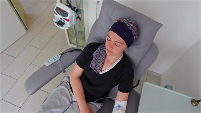 Overhead view of female cancer patient receiving chemotherapy in oncology clinic, medical treatment setting representing resilience, recovery, healing and hope