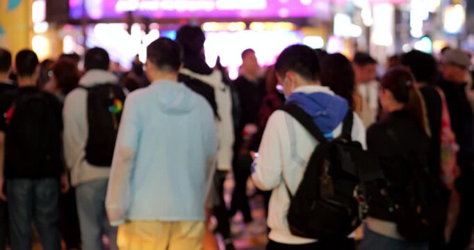 Crowded pedestrian crossing at Causeway Bay at night, slow motion shot from behind, no recognizable faces. Busy Hong Kong city life, with popular areas still filled with crowds in late evening.