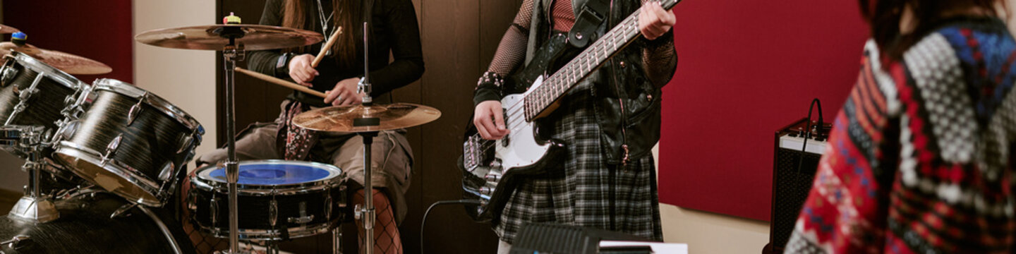Header of teenage girls performing in music group, playing drums and bass during band rehearsal, expressing youth creativity and teamwork. Ideal for music education, teen culture