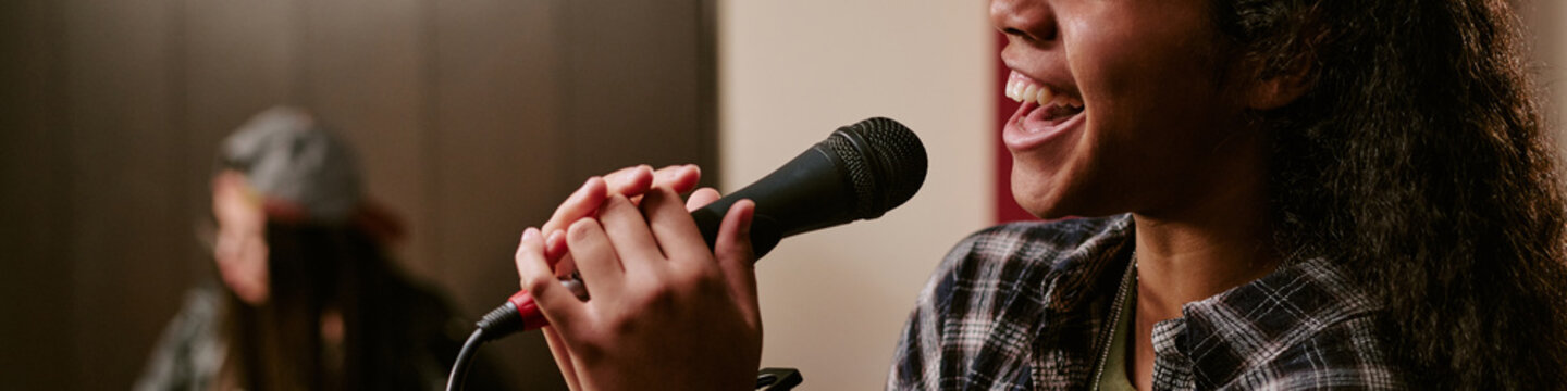 Header of teenage girl performing music group rehearsal, singing into microphone during band practice and youth entertainment production. Close up, useful for music education or teen culture marketing