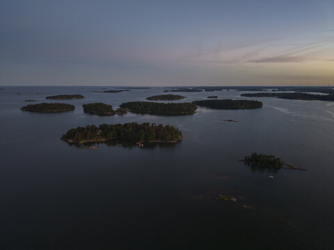 Aerial view of the Baltic Sea with numerous forested islands scattered across the calm water during the golden hour in Espoo, Uusimaa, Finland.