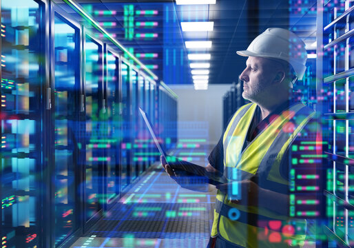 Data center operation. Engineer monitors server racks and network systems using laptop inside secure cloud infrastructure facility
