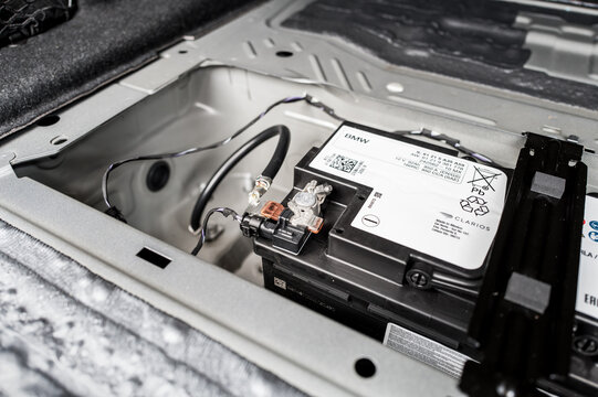 Located in the spare wheel bay of a luxury, German-built sports car, the large engine battery is located. Showing the positive and negative cables supplying the cars engine.