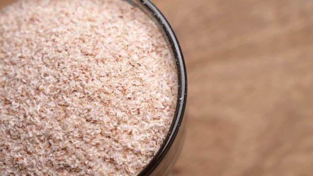 Psyllium husk in a glass bowl. Brown fibrous texture. Natural ingredient. Rotation