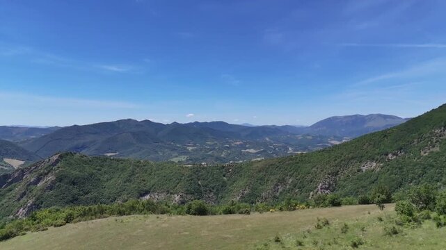 Ampio paesaggio montano con colline verdi, valli profonde e vegetazione spontanea sotto un cielo limpido. Una scena naturale luminosa che trasmette tranquillit&agrave;, vastit&agrave; e armonia con l&rsquo;ambiente