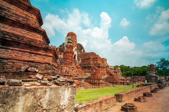 Ancient headless Buddha statues lining the red brick wall at Wat Mahathat in Ayutthaya, Thailand.