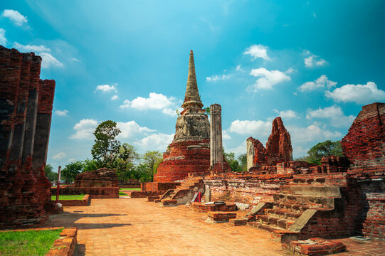 Ancient headless Buddha statues lining the red brick wall at Wat Mahathat in Ayutthaya, Thailand.