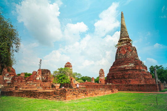 Ancient headless Buddha statues lining the red brick wall at Wat Mahathat in Ayutthaya, Thailand.