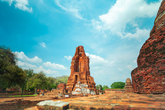 Ancient headless Buddha statues lining the red brick wall at Wat Mahathat in Ayutthaya, Thailand.