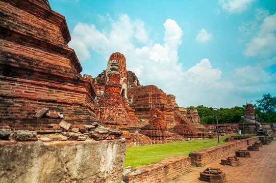 Ancient headless Buddha statues lining the red brick wall at Wat Mahathat in Ayutthaya, Thailand.
