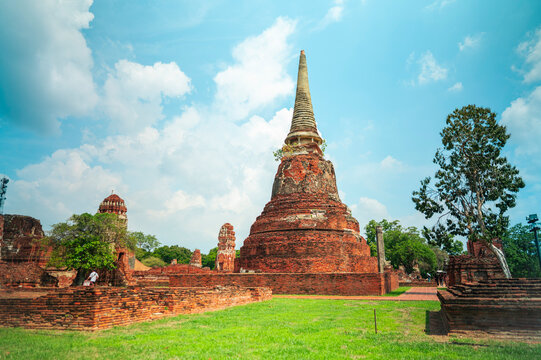 Ancient headless Buddha statues lining the red brick wall at Wat Mahathat in Ayutthaya, Thailand.