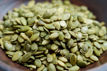 Obraz premium A close-up of fresh green pumpkin seeds in a wooden bowl