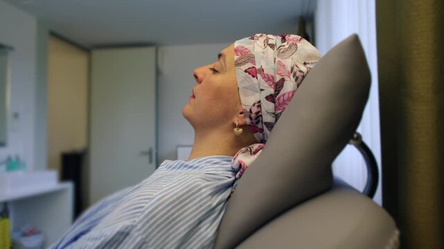 Female oncology patient reclining in treatment chair at healthcare facility, receiving medical care while demonstrating courage perseverance and hope throughout recovery journey