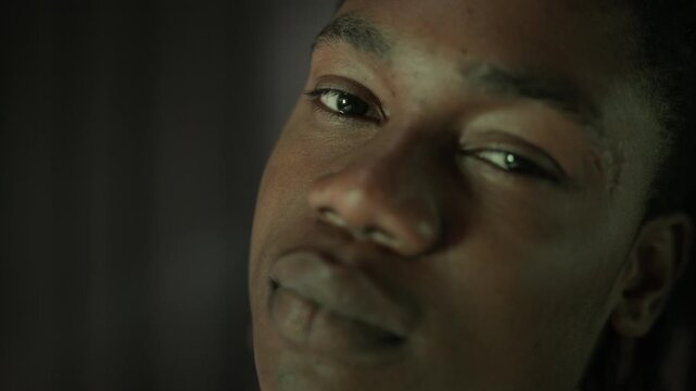 Closeup portrait of young African American man turning head in slow motion under shifting neon lights and looking into camera. Clip is ideal for gaming, cybersecurity, or digital lifestyle marketing