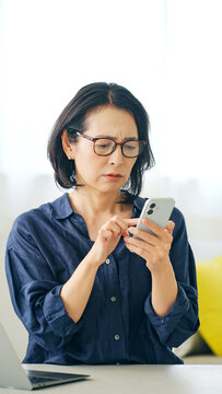 スマホを見ながら悩むミドル女性