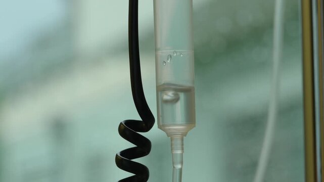 Intravenous drip chamber with fluid during medical therapy in healthcare environment, symbolizing treatment delivery, patient care, recovery, healing and clinical support