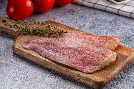 Fresh red snapper fillets on wooden board with thyme
