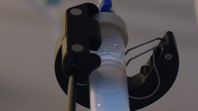 Medical drip chamber with falling fluid drops during intravenous therapy session in healthcare facility, representing treatment monitoring, recovery, healing and patient wellbeing
